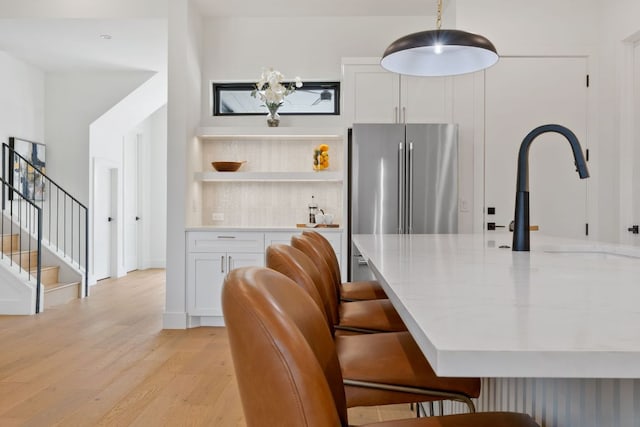 814 Stark St, Austin, TX 78756 - kitchen featuring light wood-style flooring, white cabinetry, freestanding refrigerator, a sink, and a breakfast bar area