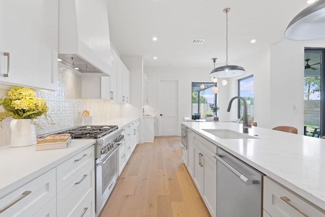 814 Stark St, Austin, TX 78756 - kitchen featuring appliances with stainless steel finishes, premium range hood, light wood-style flooring, white cabinetry, and decorative backsplash