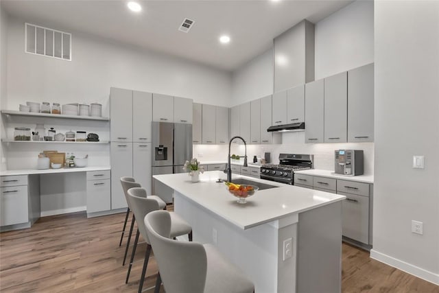 4510 Terry-O Ln Unit 141, Austin, TX 78745 - kitchen featuring stainless steel appliances, under cabinet range hood, light wood finished floors, a kitchen breakfast bar, and gray cabinets
