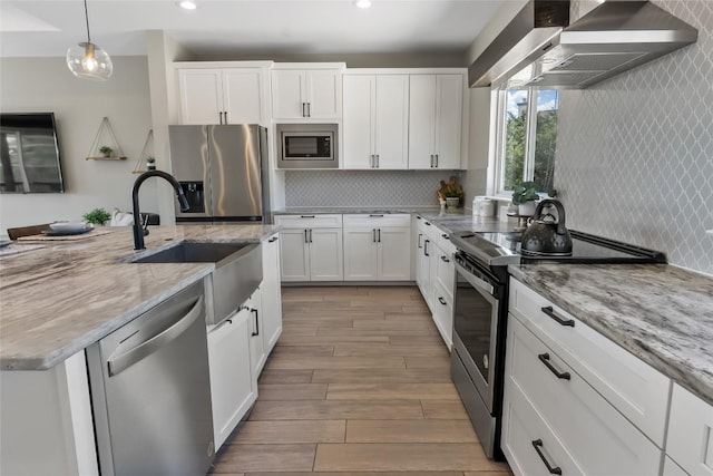 315 Southwind Rd, Point Venture, TX 78645 - kitchen featuring stainless steel appliances, wall chimney range hood, wood finished floors, recessed lighting, and white cabinetry
