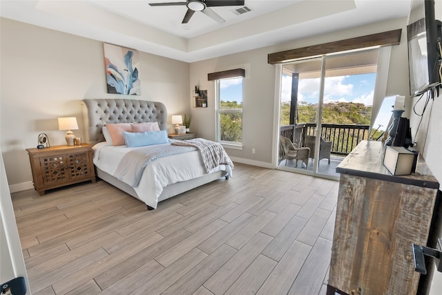 bedroom featuring visible vents, access to exterior, baseboards, a tray ceiling, and light wood finished floors