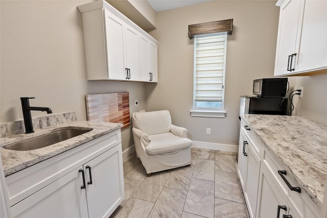 washroom featuring a sink, baseboards, cabinet space, and marble finish floor