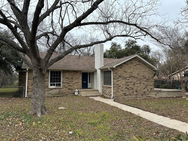 ranch-style home with brick siding, fence, and a chimney
