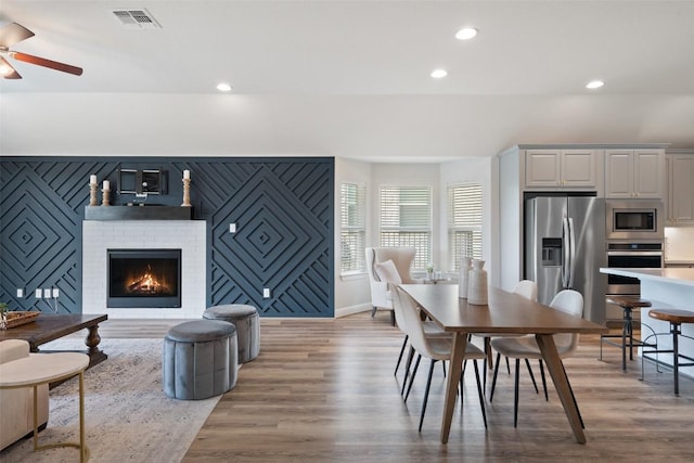 306 Gulfton St, Austin, TX 78738 - dining area with ceiling fan, recessed lighting, light wood-style flooring, a brick fireplace, and baseboards