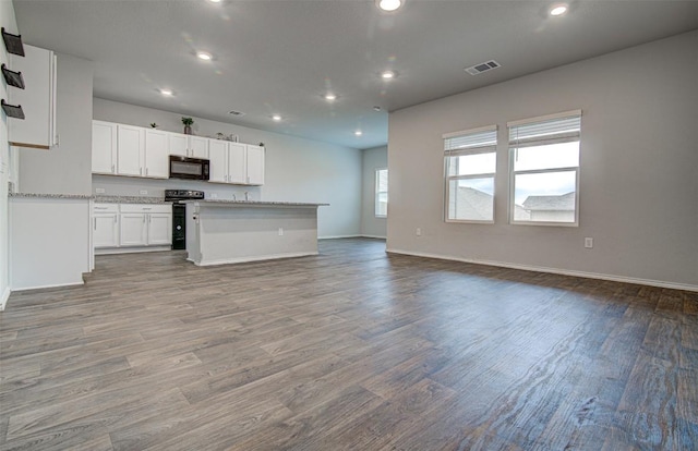 5912 Berriweather Dr, Austin, TX 78724 - kitchen with black appliances, open floor plan, recessed lighting, wood finished floors, and white cabinetry