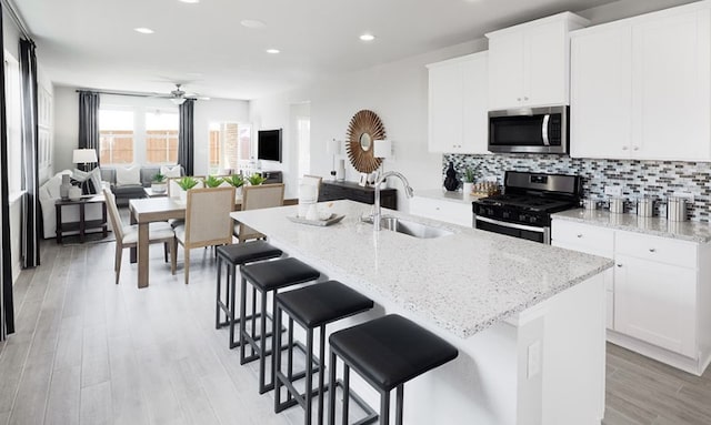 737 Drystone Trl, Liberty Hill, TX 78642 - kitchen with a sink, open floor plan, appliances with stainless steel finishes, white cabinetry, and decorative backsplash