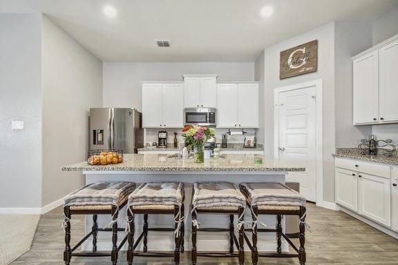 5907 Akin Run, San Antonio, TX 78261 - kitchen featuring stainless steel appliances, an island with sink, backsplash, light stone countertops, and a breakfast bar