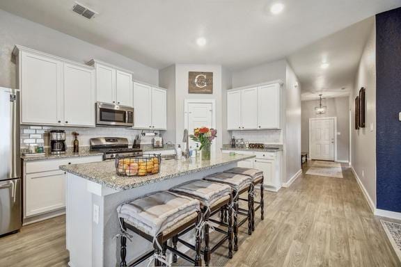 5907 Akin Run, San Antonio, TX 78261 - kitchen with appliances with stainless steel finishes, light wood-type flooring, a breakfast bar area, white cabinets, and recessed lighting