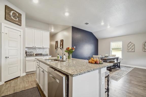5907 Akin Run, San Antonio, TX 78261 - kitchen featuring stainless steel dishwasher, a sink, light wood-style flooring, a kitchen island with sink, and white cabinetry