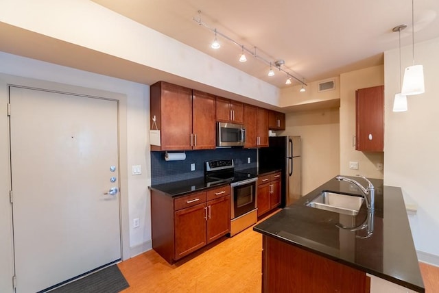 3016 Guadalupe St Unit 212, Austin, TX 78705 - kitchen with appliances with stainless steel finishes, dark countertops, light wood-style flooring, tasteful backsplash, and rail lighting