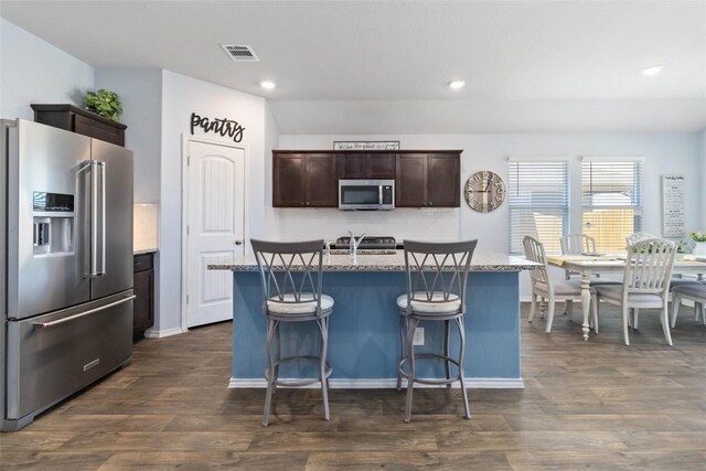 215 Whipporwill Ln, San Marcos, TX 78666 - kitchen with stainless steel appliances, dark brown cabinetry, recessed lighting, an island with sink, and dark wood-style flooring