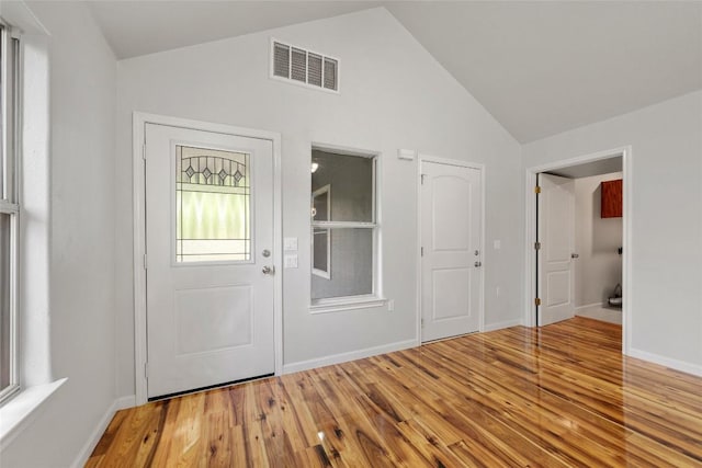 foyer with baseboards, visible vents, wood finished floors, and lofted ceiling
