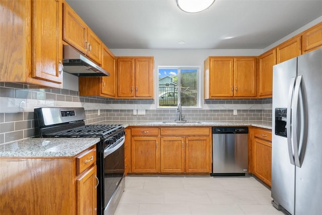 kitchen featuring brown cabinets, a sink, appliances with stainless steel finishes, and under cabinet range hood