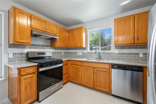kitchen with a sink, stainless steel appliances, tasteful backsplash, and under cabinet range hood