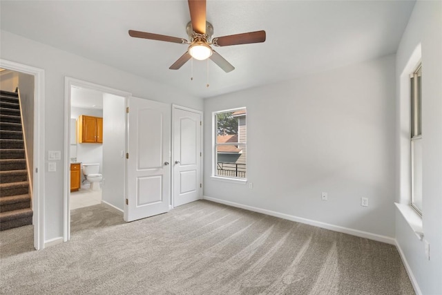 unfurnished bedroom featuring baseboards, a ceiling fan, connected bathroom, and light colored carpet