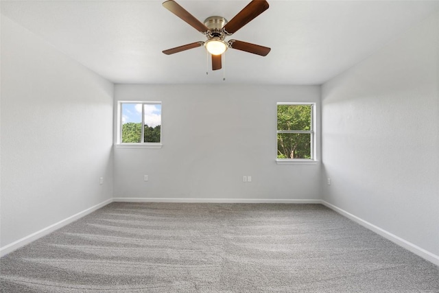 carpeted spare room featuring baseboards, ceiling fan, and plenty of natural light