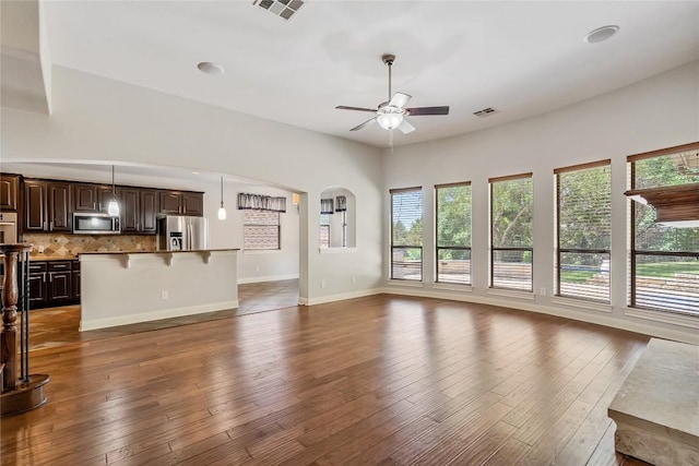 11609 Woodland Hills Trl, Austin, TX 78732 - unfurnished living room with ceiling fan, hardwood / wood-style flooring, baseboards, and arched walkways