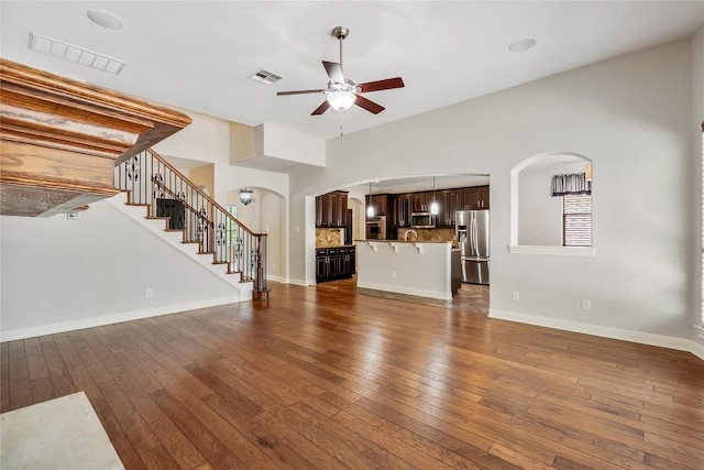 11609 Woodland Hills Trl, Austin, TX 78732 - unfurnished living room featuring arched walkways, a ceiling fan, hardwood / wood-style flooring, stairway, and baseboards