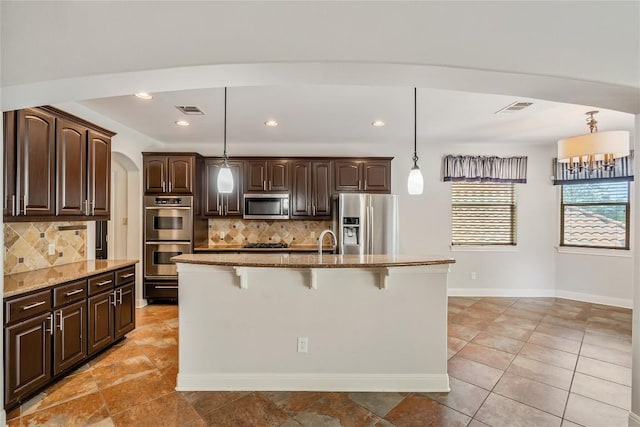 11609 Woodland Hills Trl, Austin, TX 78732 - kitchen featuring stainless steel appliances, a kitchen breakfast bar, light stone counters, dark brown cabinets, and recessed lighting
