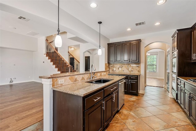 11609 Woodland Hills Trl, Austin, TX 78732 - kitchen with arched walkways, a sink, dishwasher, dark brown cabinets, and recessed lighting