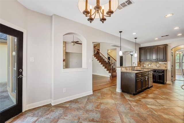 11609 Woodland Hills Trl, Austin, TX 78732 - kitchen with arched walkways, a sink, dark brown cabinets, baseboards, and hanging light fixtures