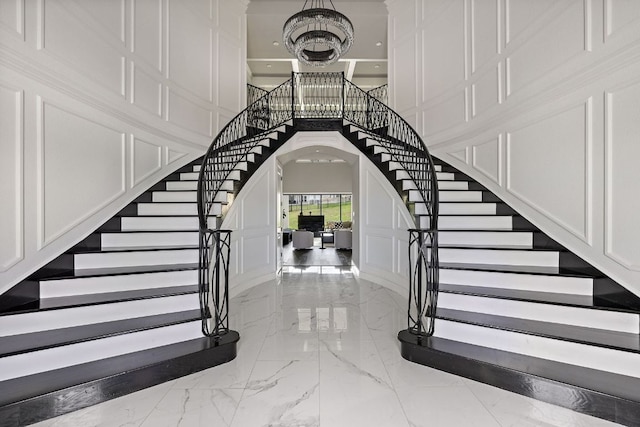 4525 Via Roma Pass, Leander, TX 78641 - staircase featuring a decorative wall, marble tiled flooring, arched walkways, a high ceiling, and a chandelier
