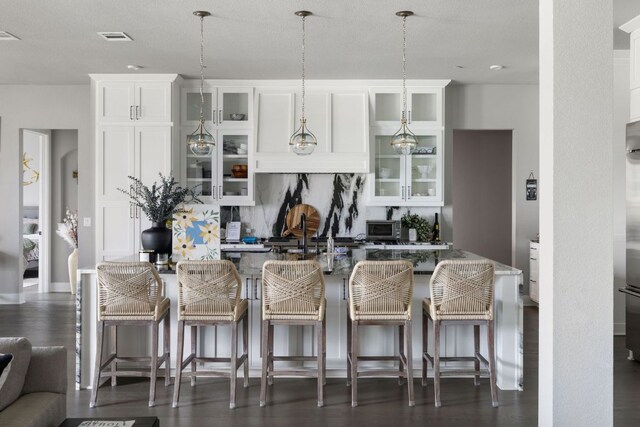 4525 Via Roma Pass, Leander, TX 78641 - kitchen with an island with sink, decorative light fixtures, a kitchen breakfast bar, and white cabinets