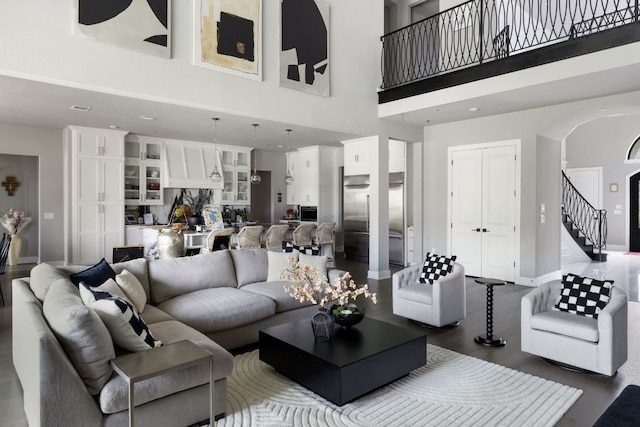 4525 Via Roma Pass, Leander, TX 78641 - living area featuring a towering ceiling, arched walkways, dark wood-type flooring, baseboards, and stairs