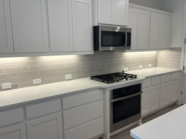 19316 Fernando Trl, Austin, TX 78738 - kitchen featuring tasteful backsplash, white cabinets, light countertops, appliances with stainless steel finishes, and dark wood finished floors