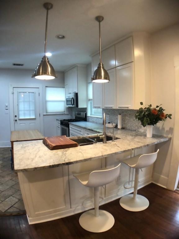 900 W Lynn St, Austin, TX 78703 - kitchen with appliances with stainless steel finishes, a peninsula, dark wood-style floors, backsplash, and baseboards