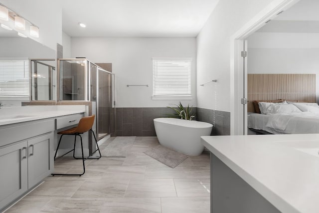 134 Soft Elm Dr, Buda, TX 78610 - full bathroom with vanity, a shower stall, tile walls, a freestanding tub, and connected bathroom