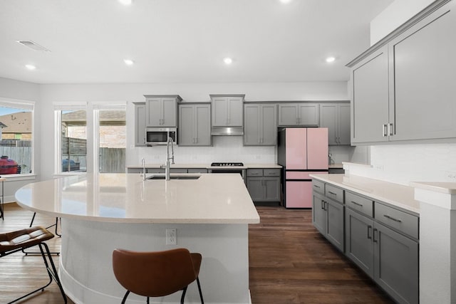 134 Soft Elm Dr, Buda, TX 78610 - kitchen with gray cabinetry, freestanding refrigerator, stainless steel microwave, a sink, and tasteful backsplash