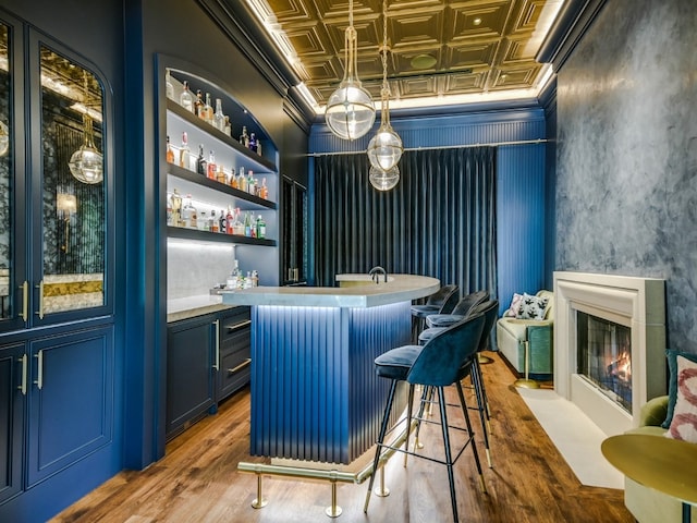 1614 Bruton Springs Rd, Austin, TX 78733 - indoor wet bar with an ornate ceiling, a fireplace with flush hearth, wood finished floors, and ornamental molding