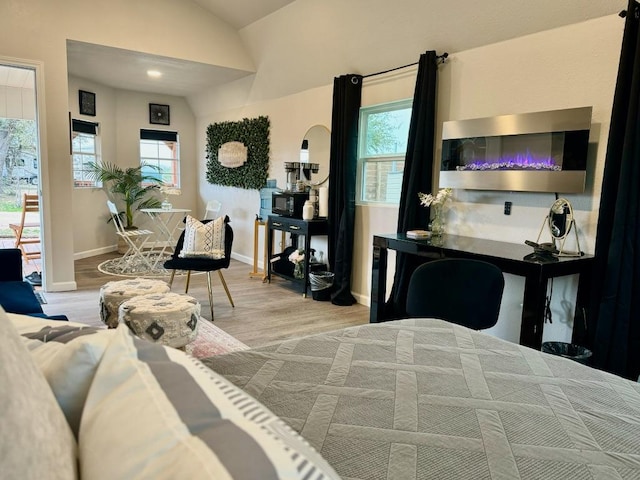 bedroom featuring vaulted ceiling, wood finished floors, and multiple windows