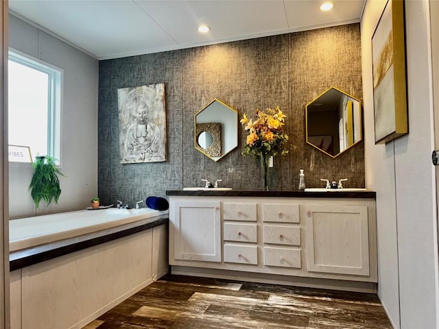 full bathroom featuring a bath, wood finished floors, a sink, and double vanity