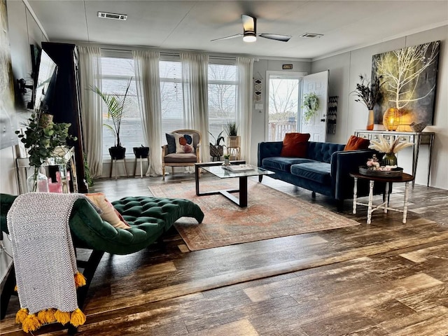 interior space with wood finished floors, a ceiling fan, visible vents, and crown molding