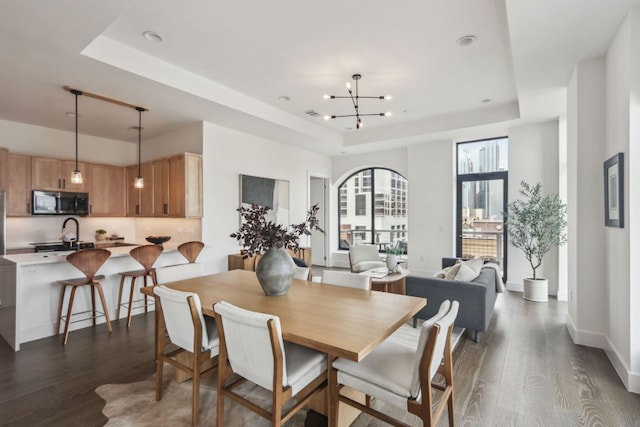 507 Sabine St Unit 601, Austin, TX 78701 - dining area with a tray ceiling, dark wood finished floors, a chandelier, recessed lighting, and baseboards
