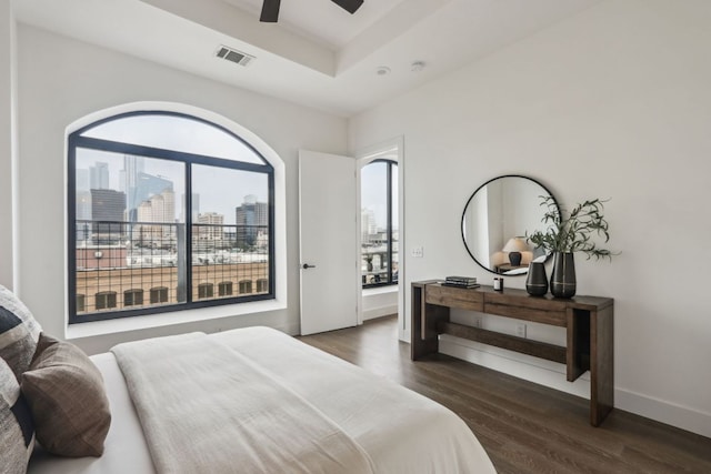 507 Sabine St Unit 601, Austin, TX 78701 - bedroom featuring dark wood-type flooring, a city view, a raised ceiling, baseboards, and a ceiling fan