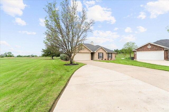 125 Fairway Ct, Bastrop, TX 78602 - view of front of home featuring driveway, a front yard, brick siding, a chimney, and a garage
