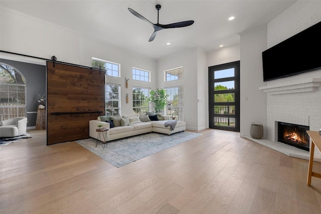 611 Ladin Ln, Lakeway, TX 78734 - living room featuring ceiling fan, light wood finished floors, a fireplace, recessed lighting, and a barn door