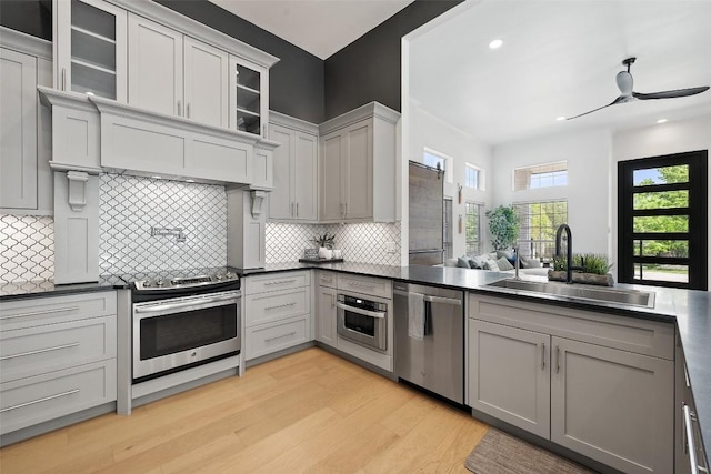 611 Ladin Ln, Lakeway, TX 78734 - kitchen featuring stainless steel appliances, light wood-style flooring, dark countertops, ceiling fan, and decorative backsplash
