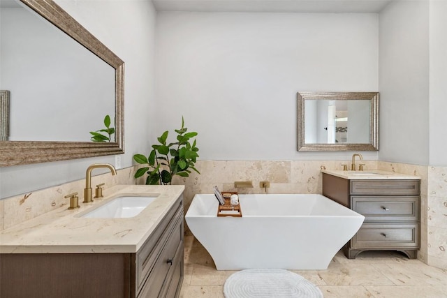 611 Ladin Ln, Lakeway, TX 78734 - bathroom featuring tile walls, two vanities, a freestanding tub, and wainscoting