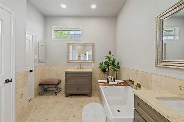 611 Ladin Ln, Lakeway, TX 78734 - full bath featuring tile walls, two vanities, a soaking tub, a wainscoted wall, and recessed lighting