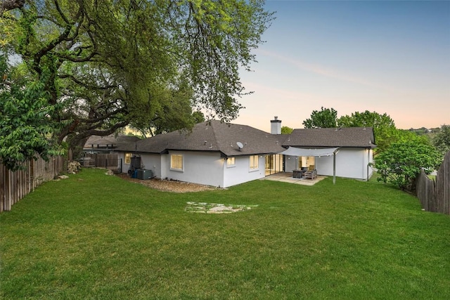 611 Ladin Ln, Lakeway, TX 78734 - back of house at dusk with a patio, a fenced backyard, and a chimney