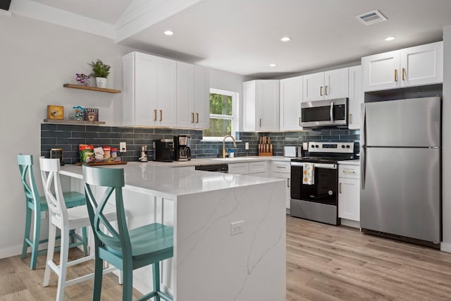 12635 Live Oak Ln, Buda, TX 78610 - kitchen featuring appliances with stainless steel finishes, a peninsula, light stone counters, tasteful backsplash, and a sink