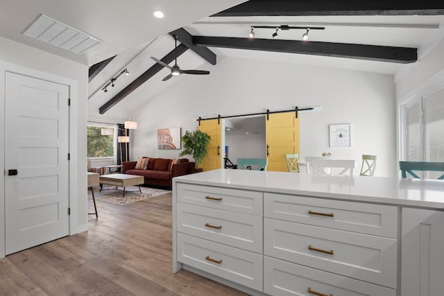 12635 Live Oak Ln, Buda, TX 78610 - kitchen featuring a barn door, ceiling fan, light wood-style floors, light countertops, and white cabinets