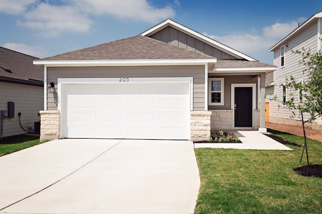 205 Escape Way, Jarrell, TX 76537 - view of front of home with driveway, a shingled roof, a front lawn, a garage, and board and batten siding