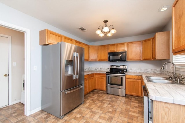 7201 Pappus Ct, Temple, TX 76502 - kitchen with stainless steel appliances, tile counters, a chandelier, brick patterned flooring, and recessed lighting