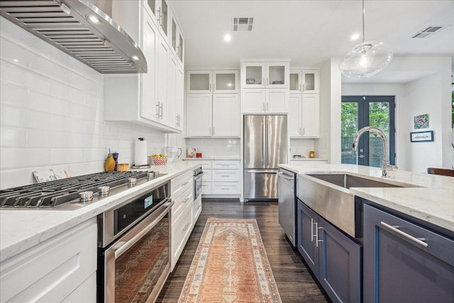 1303 Harriet Ct Unit A, Austin, TX 78756 - kitchen featuring premium range hood, stainless steel appliances, dark wood-type flooring, white cabinets, and backsplash