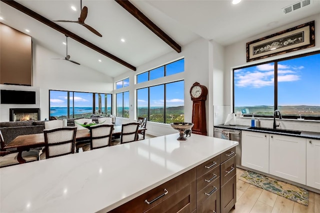 8612 Tip Top Dr Unit 2, Jonestown, TX 78645 - kitchen with a sink, ceiling fan, beam ceiling, light wood finished floors, and a lit fireplace
